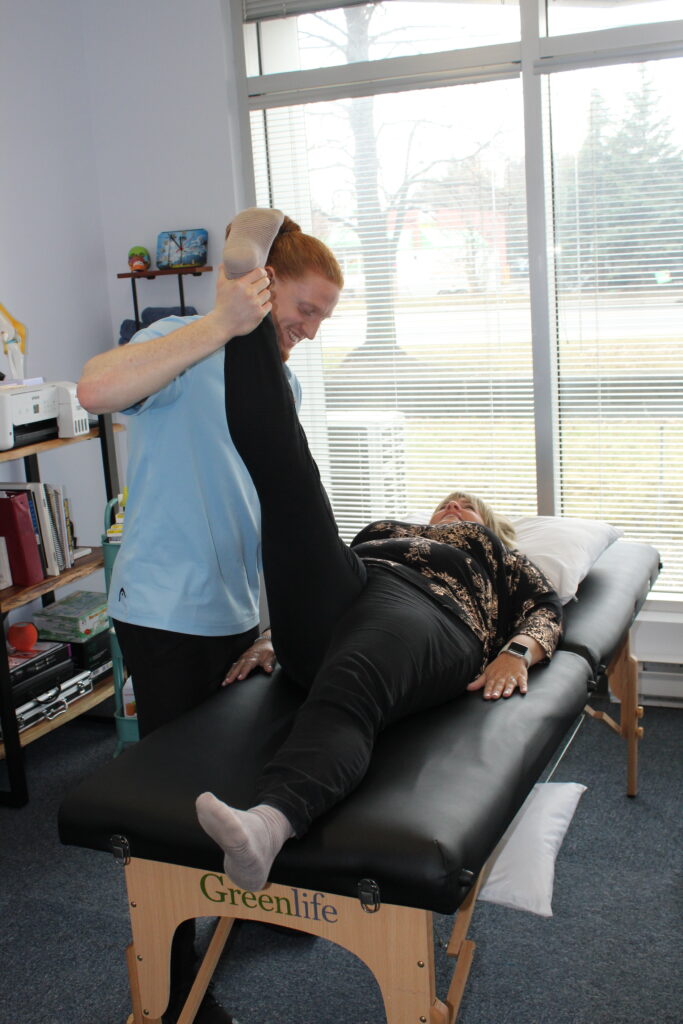 Physiotherapist helping patient with leg stretch indoors